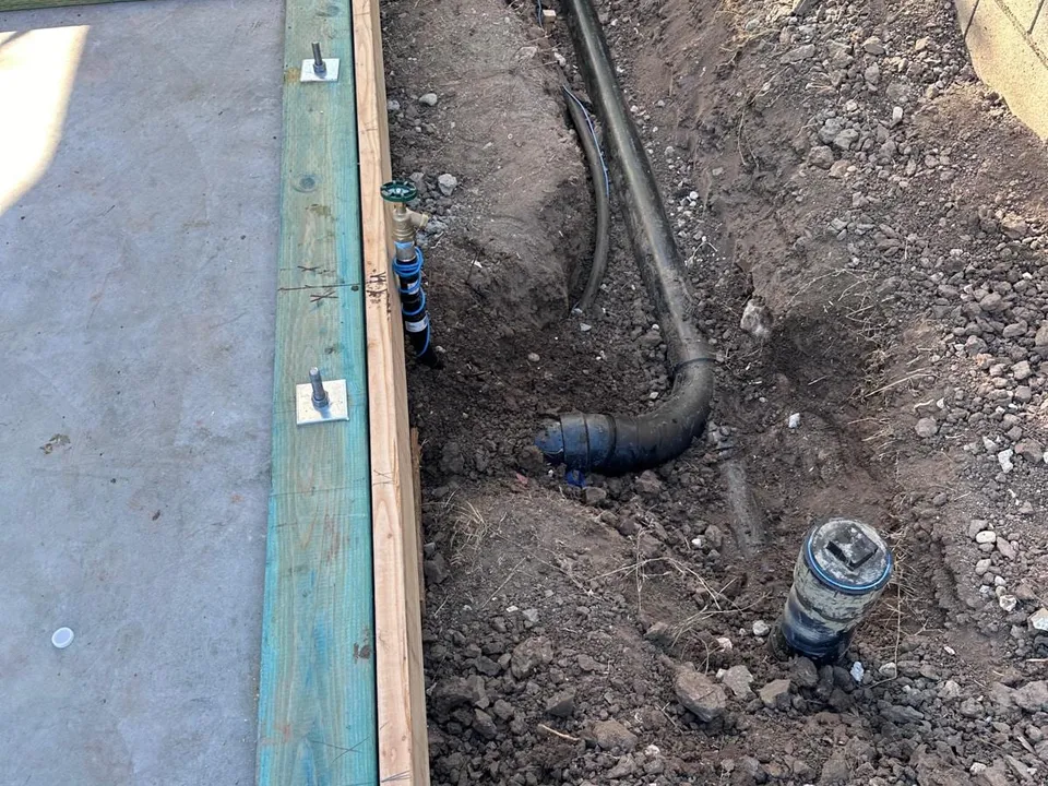 A drain line and a cleanout fitting in a trench dug along a house foundation